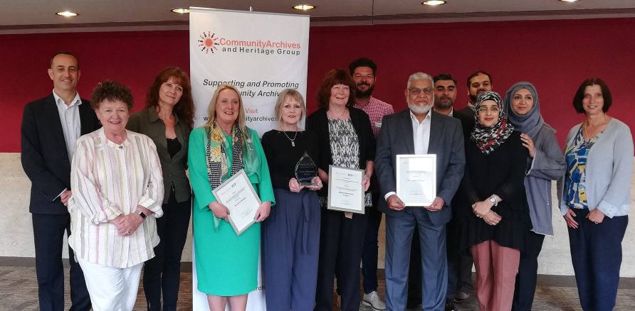 The award winners at the CAHG 2019 Conference. The award winners at the CAHG 2019 Conference. A line of people stand in front of a banner for the conference.